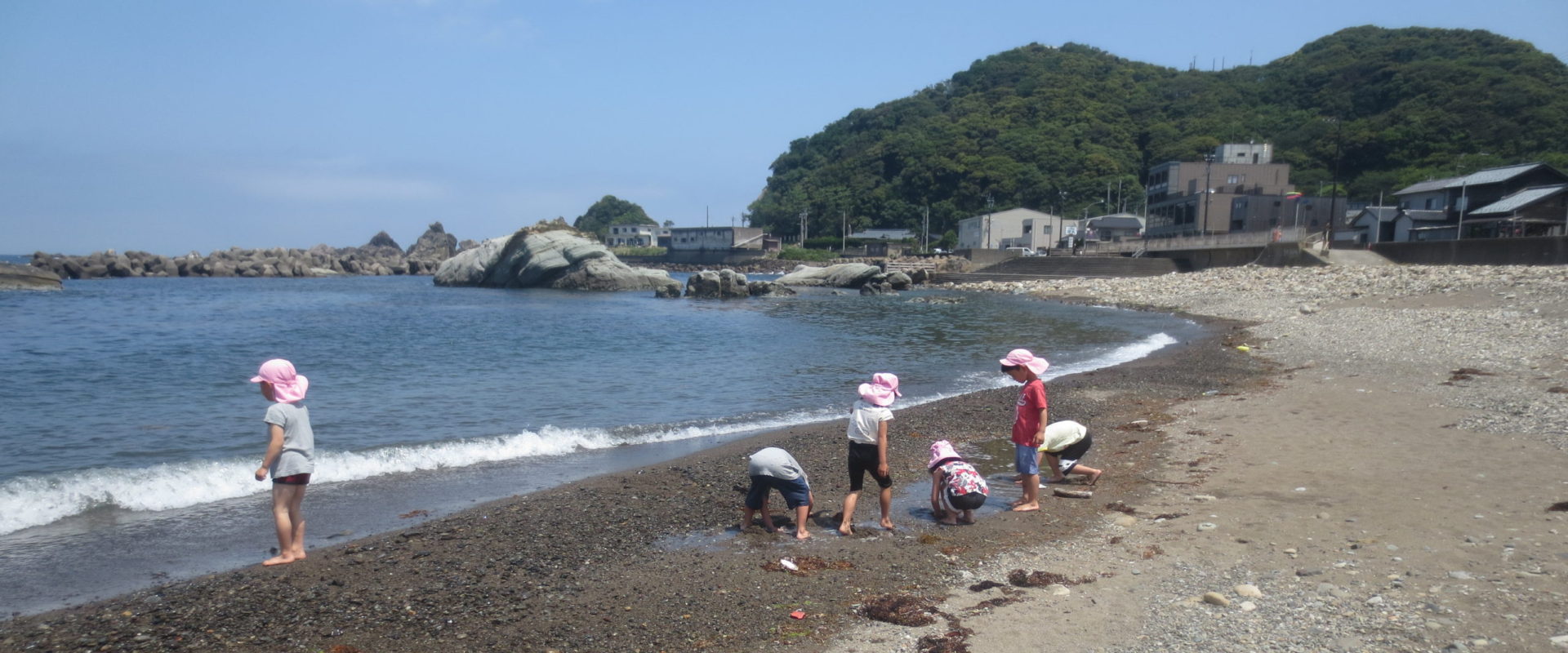 海辺での入居者の活動。砂浜で複数名が水遊びや散策を楽しんでいます。